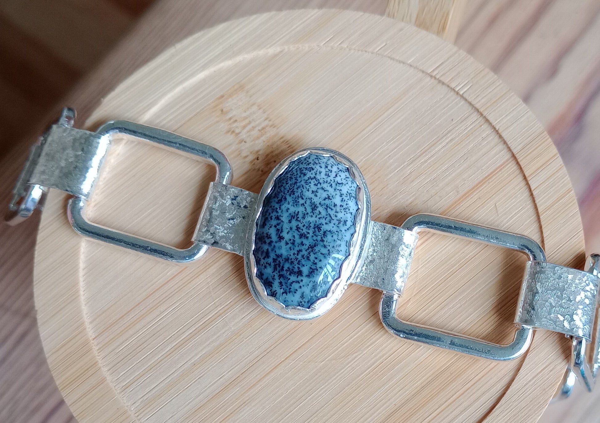 Silver bracelet with a blue speckled stone on a wooden surface